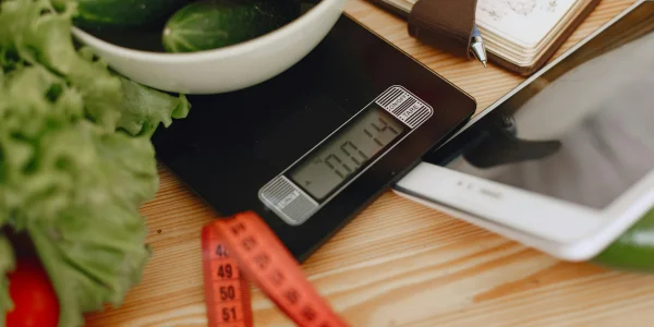Báscula de cocina digital moderna sobre encimera de madera pesando alimentos frescos para una dieta saludable