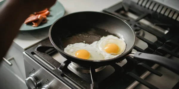 Sartén antiadherente sobre una placa de gas cocinando huevos fritos sin tóxicos